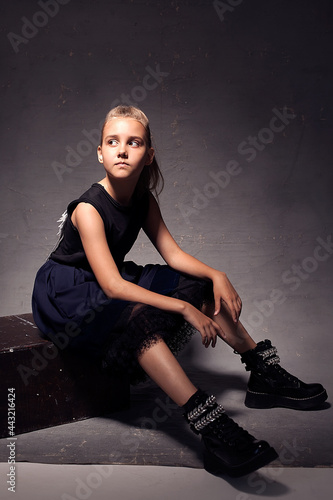 Portrait of a little girl 8-10 years old in a dark fluffy skirt, isolated on a dark background of the studio.