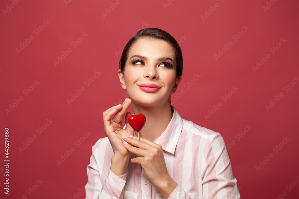 Young beautiful woman wearing shirt smiling in love showing heart symbol and shape in hands on red background Young beautiful woman wearing shirt smiling in love showing heart symbol and shape in hands on red background