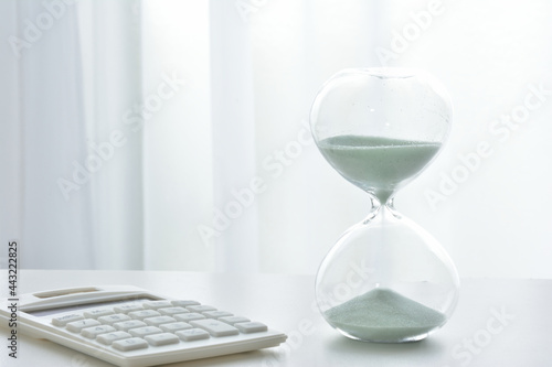 Hourglass on a white desk photo
