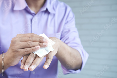  man disinfecting his hands with a wet wipe.