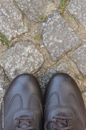 Brown leather shoes for men on footpath made of rocks or stones. Male footwear. Copy space for text