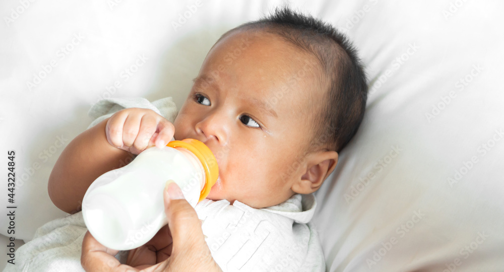 Portrait of enjoy happy love family asian mother playing with adorable little asian baby.Mom feeding bottle of milk to cute son in a white bedroom.Love of family concept Portrait of enjoy happy love family asian mother playing with adorable little asian baby.Mom feeding bottle of milk to cute son in a white bedroom.Love of family concept