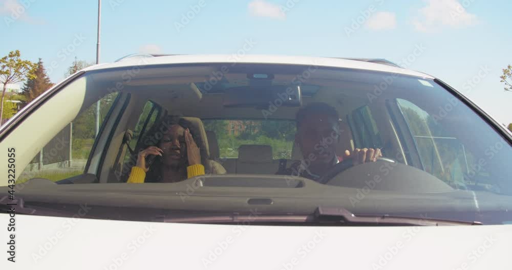 Man and woman sitting in car, man is driving and girl is talking on phone. Tired young woman looking unhappy. Car's interior. Man and woman sitting in car, man is driving and girl is talking on phone. Tired young woman looking unhappy. Car's interior.