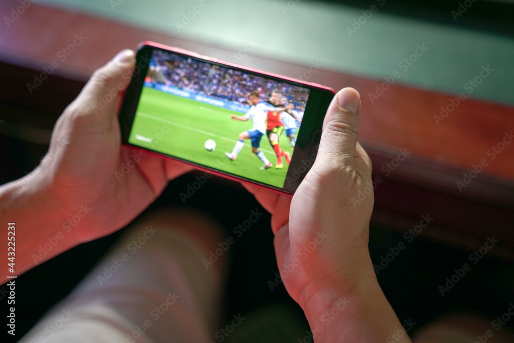 Man watching football and sport stream on mobile phone. Close up view. Home entertainment concept.