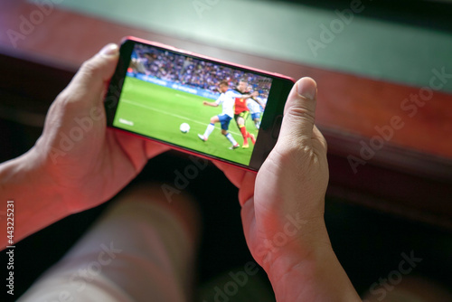Man watching football and sport stream on mobile phone. Close up view. Home entertainment concept.