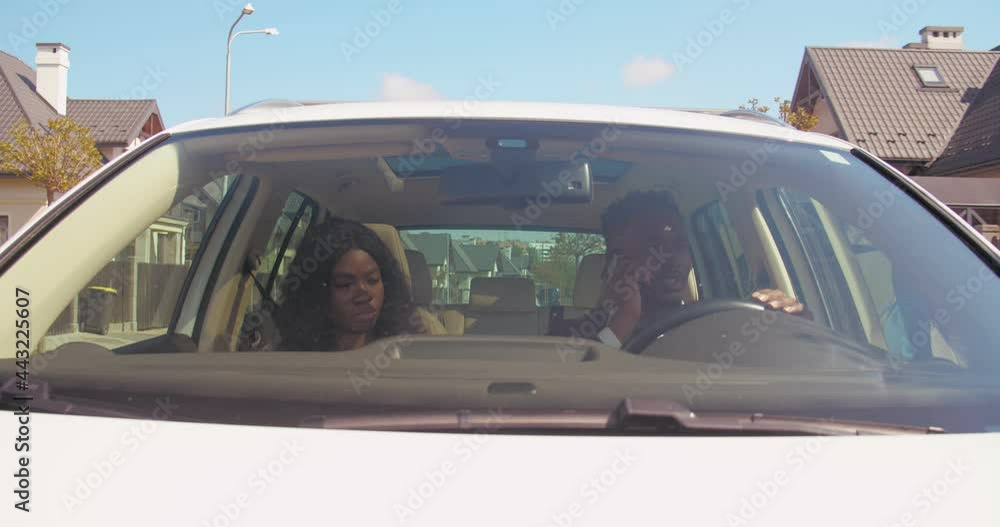 Man and woman sitting in car, man is driving and talking on phone. Tired young woman looking unhappy. Car's interior. Man and woman sitting in car, man is driving and talking on phone. Tired young woman looking unhappy. Car's interior.