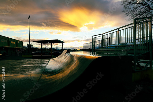 Skate park ramp at twilight with last golden sunlight reflected off surface, no people