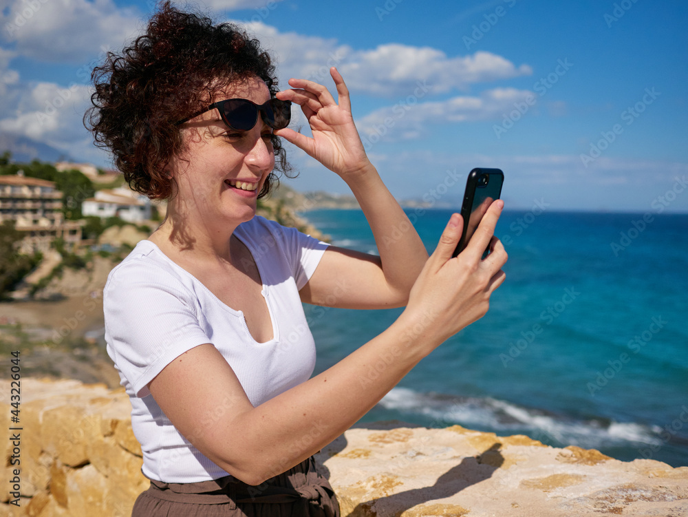 Woman looking at the mobile on the Mediterranean coast
