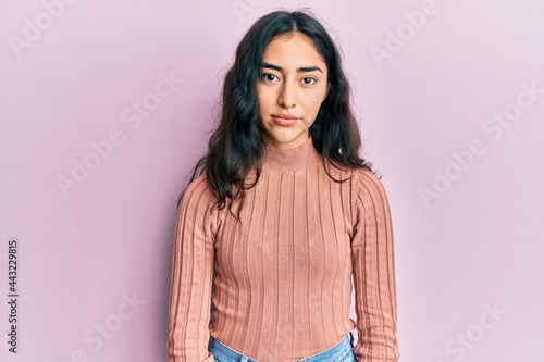 Hispanic teenager girl with dental braces wearing casual clothes with serious expression on face. simple and natural looking at the camera.