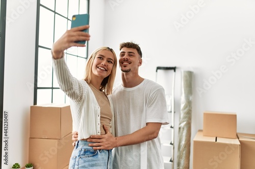 Young caucasian couple smiling happy making selfie by the smartphone at new home.