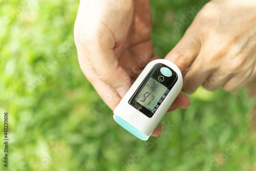 Asian Man measuring oxygen level with modern fingertip pulse oximeter using for measuring heart rate checking oxygen saturation level in the blood diagnosis of Coronavirus or COVID-19 medical concept