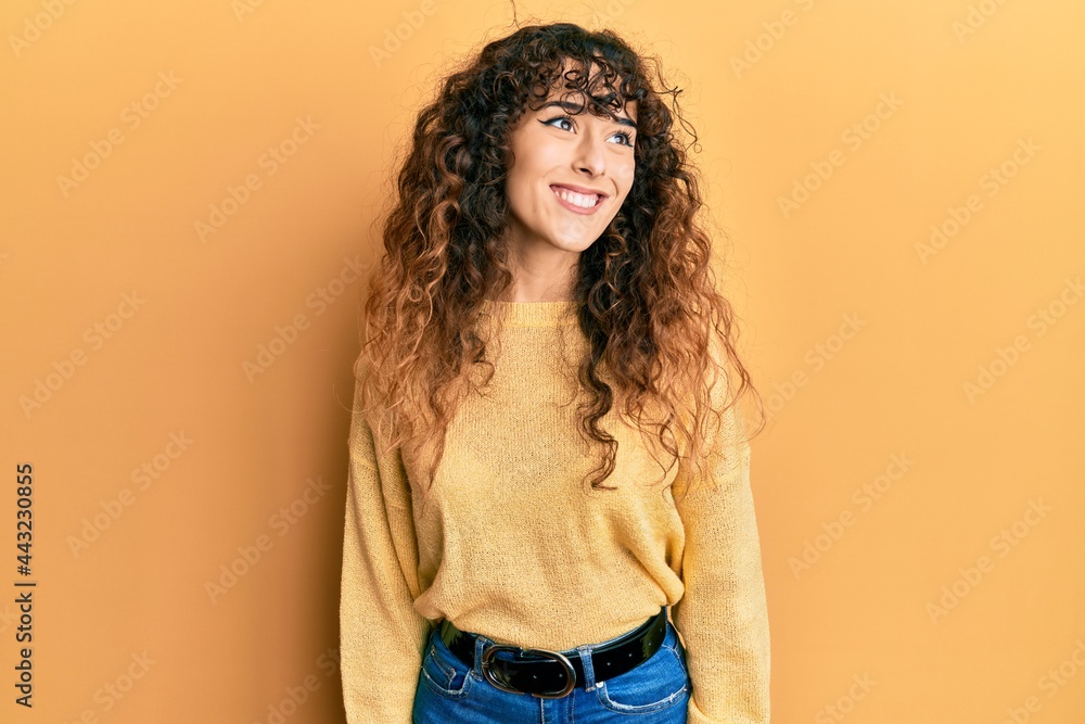 Young hispanic girl wearing casual clothes looking away to side with smile on face, natural expression. laughing confident. Young hispanic girl wearing casual clothes looking away to side with smile on face, natural expression. laughing confident.