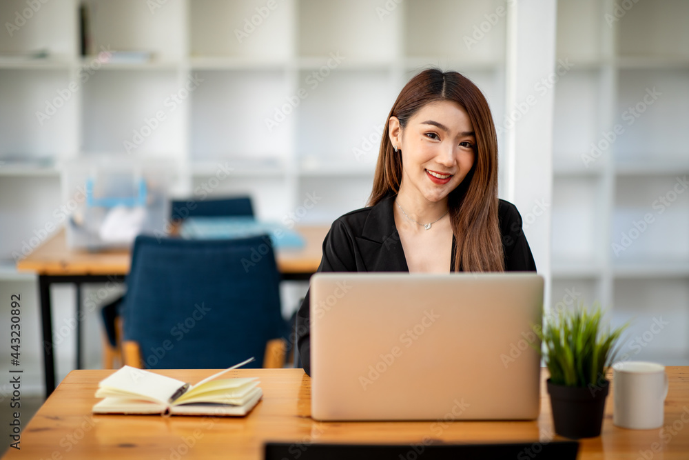 Portrait of Confident asian young business woman working on laptop at her workplace at modern office.Blurred background Portrait of Confident asian young business woman working on laptop at her workplace at modern office.Blurred background