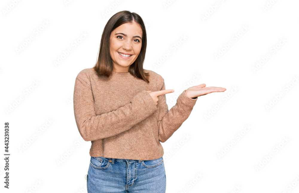 Young beautiful woman wearing casual clothes amazed and smiling to the camera while presenting with hand and pointing with finger. Young beautiful woman wearing casual clothes amazed and smiling to the camera while presenting with hand and pointing with finger.