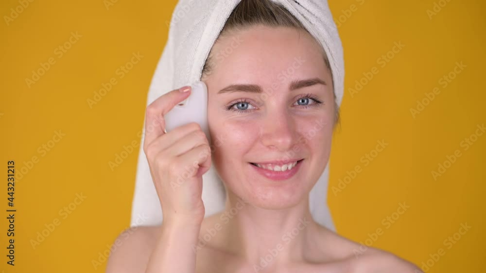Young attractive girl with a towel on her head massaged face by scrapering gua sha. Skincare concept. Young attractive girl with a towel on her head massaged face by scrapering gua sha. Skincare concept.