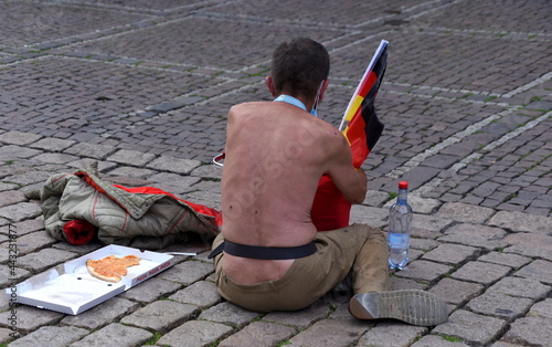 Bettler mit nacktem Oberkörper auf Kopfsteinpflaster sitzend photo