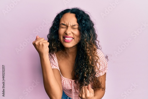 Young latin woman wearing casual clothes celebrating surprised and amazed for success with arms raised and eyes closed