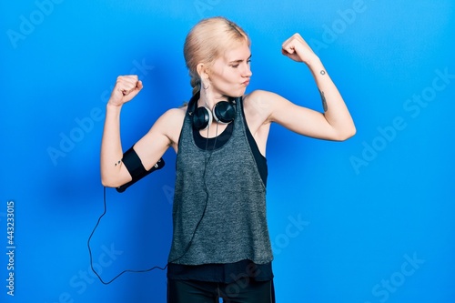 Beautiful caucasian woman with blond hair wearing sportswear showing arms muscles smiling proud. fitness concept.