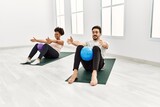 Young african american woman and hispanic man exercising at pilates room, stretching body and doing yoga pose, training strength and balance