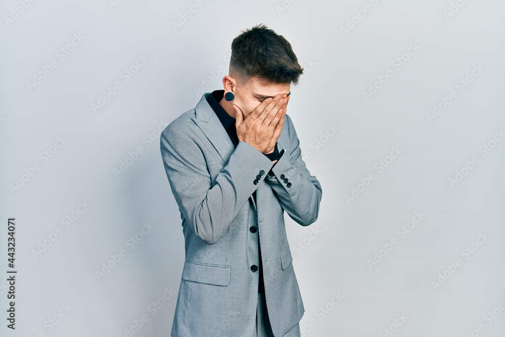 Young caucasian boy with ears dilation wearing business jacket with sad expression covering face with hands while crying. depression concept. Young caucasian boy with ears dilation wearing business jacket with sad expression covering face with hands while crying. depression concept.