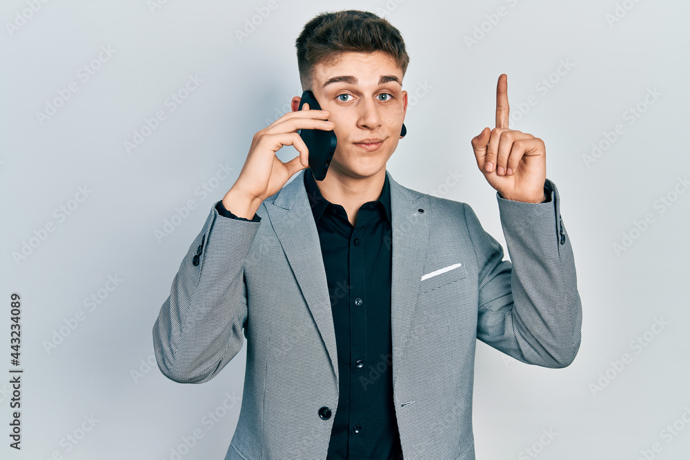 Young caucasian boy with ears dilation having conversation talking on the smartphone smiling with an idea or question pointing finger with happy face, number one Young caucasian boy with ears dilation having conversation talking on the smartphone smiling with an idea or question pointing finger with happy face, number one