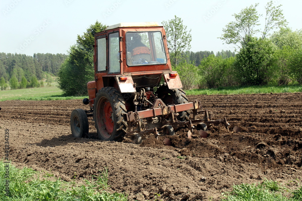 Obraz premium Red tractor making paths for planting potatoes