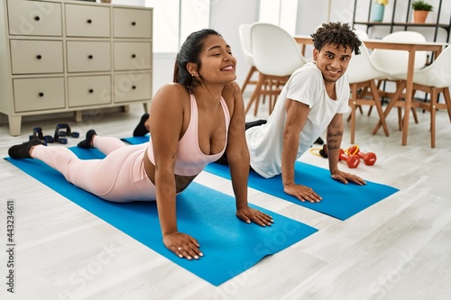 Young latin couple smiling happy training yoga pose at home.