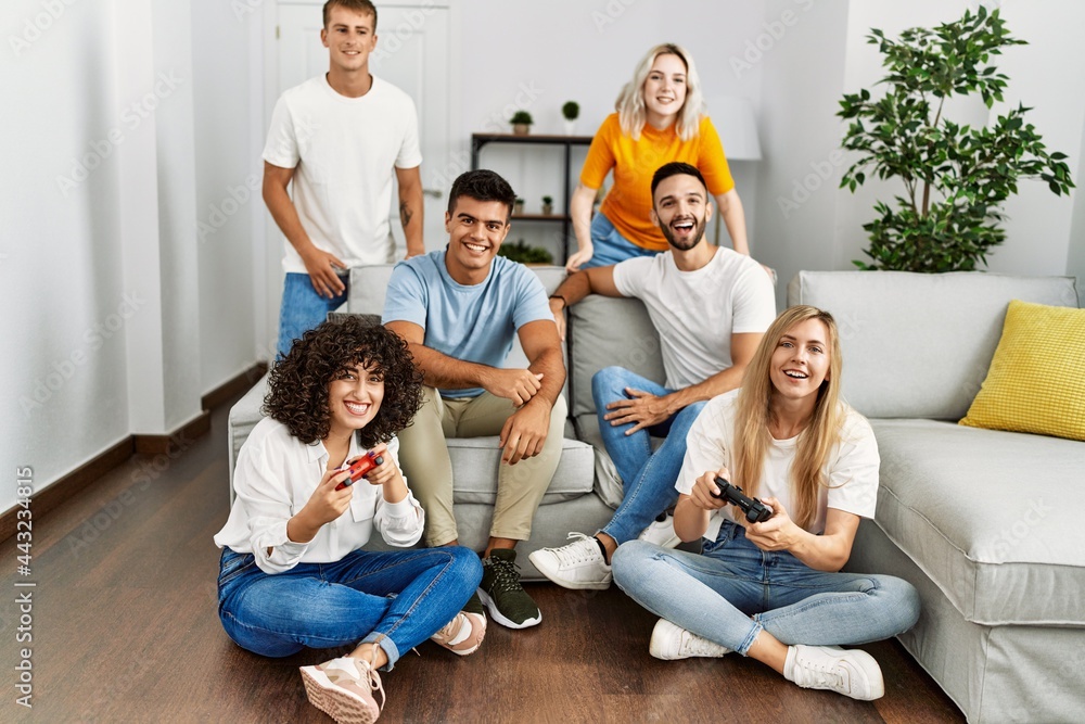 Group of young friends smiling happy playing video game at home.
