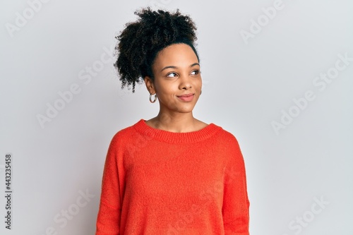 Young african american girl wearing casual clothes smiling looking to the side and staring away thinking.