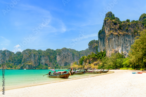 Railay beach west with exotic limestone cliff mountain and longtail wooden tourist boat, Krabi, Thailand