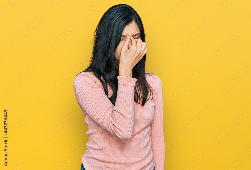 Young hispanic woman wearing casual clothes tired rubbing nose and eyes feeling fatigue and headache. stress and frustration concept. Young hispanic woman wearing casual clothes tired rubbing nose and eyes feeling fatigue and headache. stress and frustration concept.