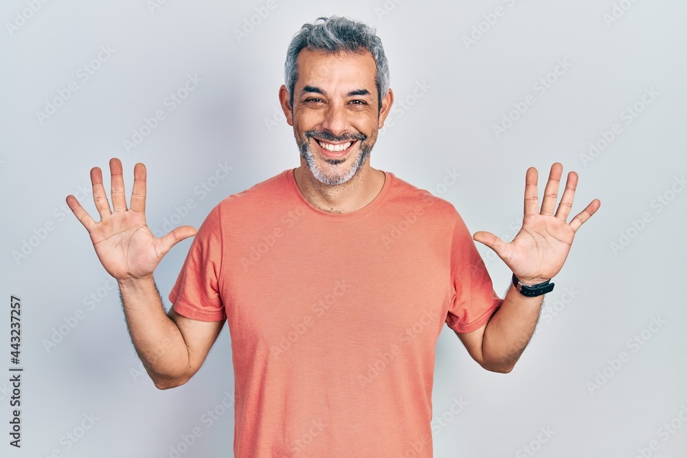 Fototapeta premium Handsome middle age man with grey hair wearing casual t shirt showing and pointing up with fingers number ten while smiling confident and happy.