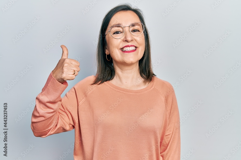 Middle age hispanic woman wearing casual clothes and glasses smiling happy and positive, thumb up doing excellent and approval sign Middle age hispanic woman wearing casual clothes and glasses smiling happy and positive, thumb up doing excellent and approval sign