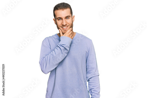 Young caucasian man wearing casual clothes looking confident at the camera smiling with crossed arms and hand raised on chin. thinking positive.