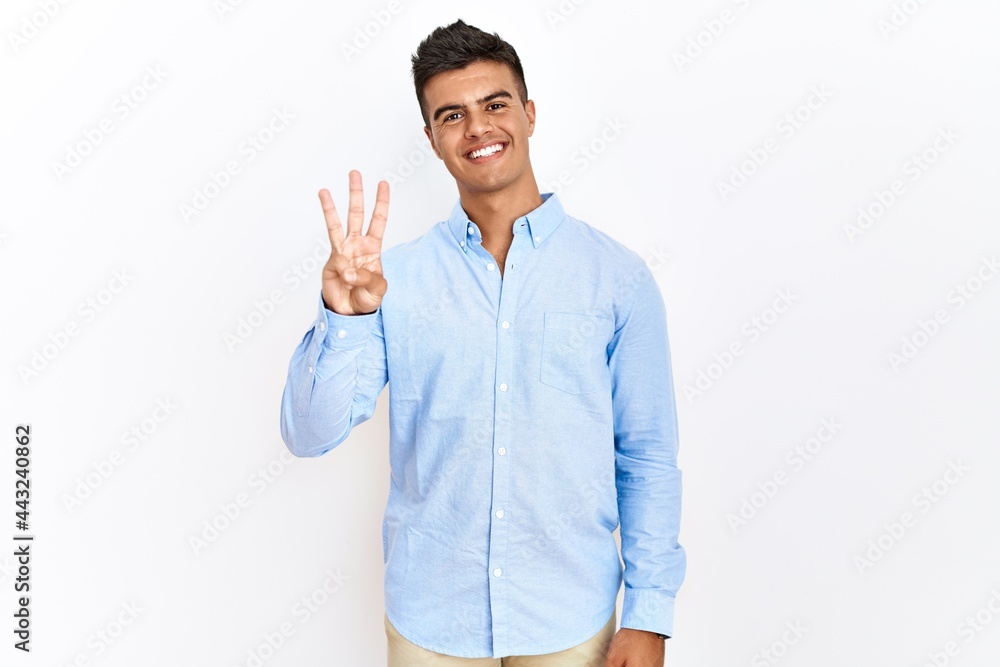 Young hispanic man wearing business shirt standing over isolated background showing and pointing up with fingers number three while smiling confident and happy. Young hispanic man wearing business shirt standing over isolated background showing and pointing up with fingers number three while smiling confident and happy.