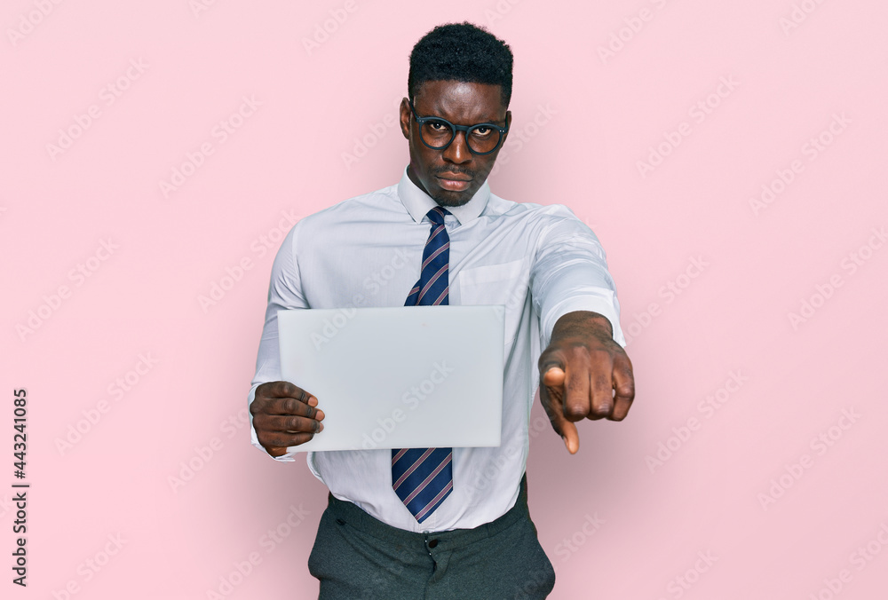 Handsome business black man holding blank empty banner pointing with finger to the camera and to you, confident gesture looking serious