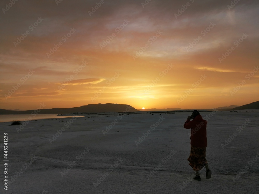 silhouette of person walking on the beach at sunrise