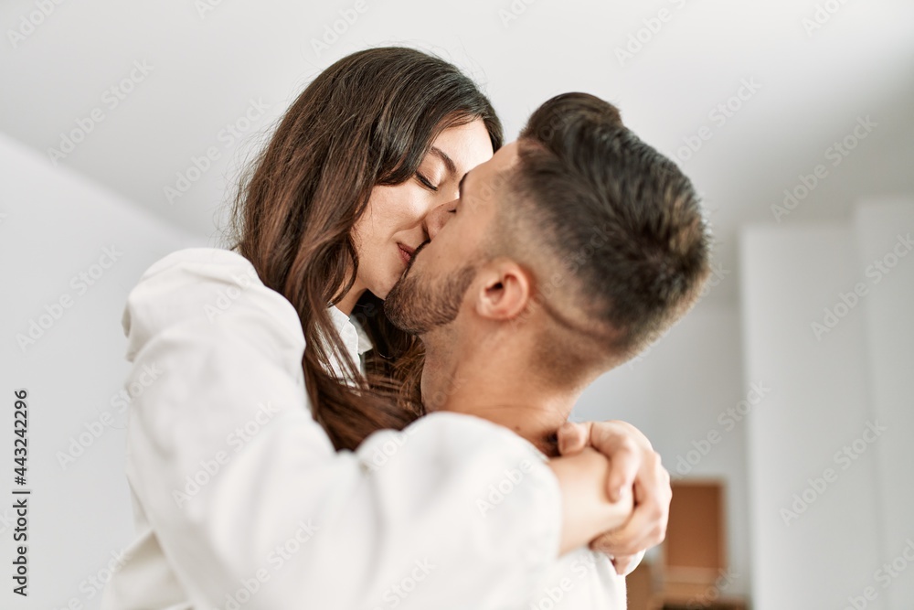 Young hispanic man holding woman in arms and hugging at new home. Young hispanic man holding woman in arms and hugging at new home.