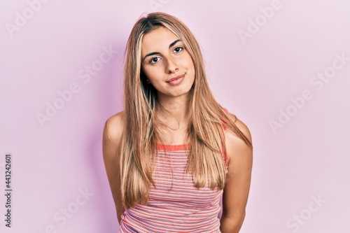 Beautiful hispanic woman wearing casual summer t shirt relaxed with serious expression on face. simple and natural looking at the camera.