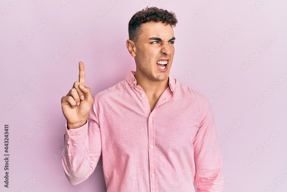 Hispanic young man pointing up with fingers angry and mad screaming frustrated and furious, shouting with anger. rage and aggressive concept. Hispanic young man pointing up with fingers angry and mad screaming frustrated and furious, shouting with anger. rage and aggressive concept.
