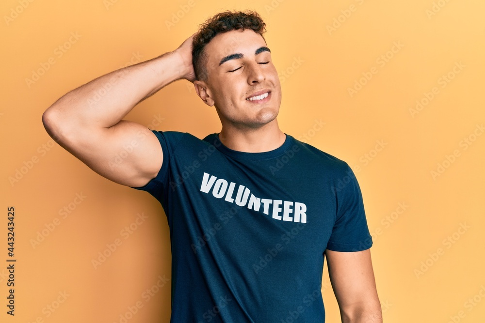 Hispanic young man wearing volunteer t shirt smiling confident touching hair with hand up gesture, posing attractive and fashionable Hispanic young man wearing volunteer t shirt smiling confident touching hair with hand up gesture, posing attractive and fashionable