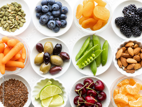 Top down view of several small dishes filled with various types of fresh whole raw foods.