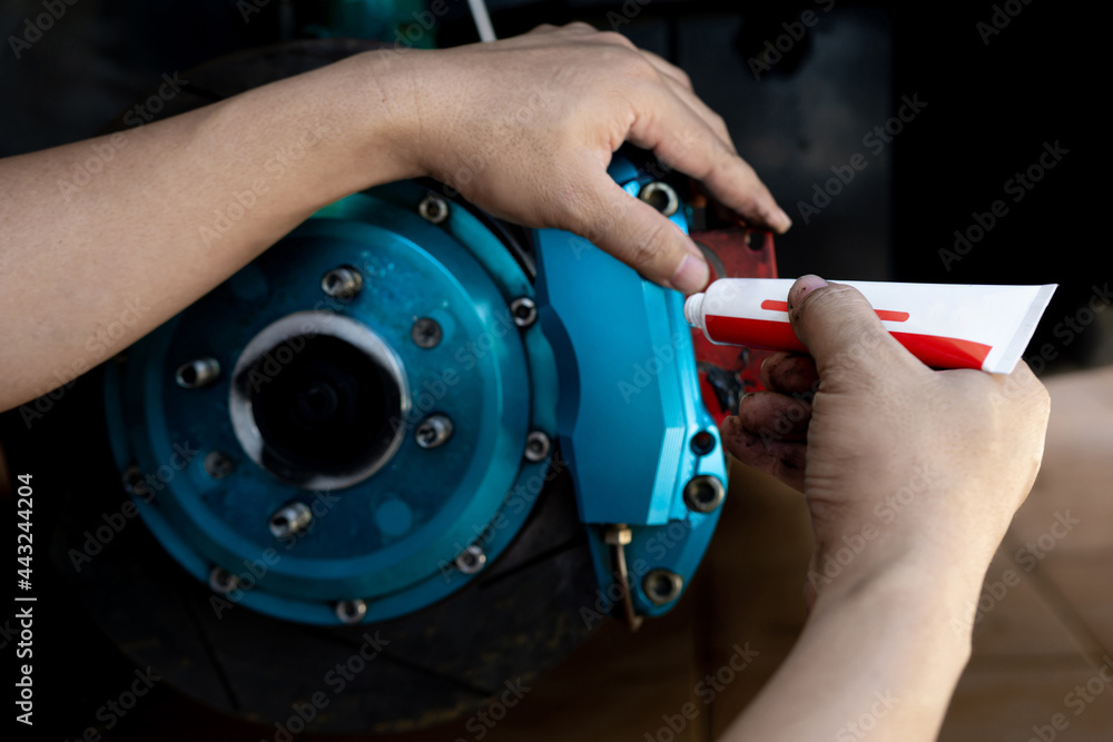 Disk brake service concept : Close up hand a man use Grease Anti-seize to brake pad and cleaning system in service shop Disk brake service concept : Close up hand a man use Grease Anti-seize to brake pad and cleaning system in service shop