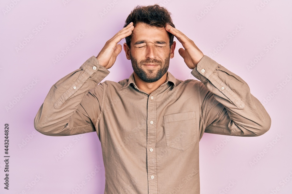 Handsome man with beard wearing casual shirt with hand on head, headache because stress. suffering migraine. Handsome man with beard wearing casual shirt with hand on head, headache because stress. suffering migraine.