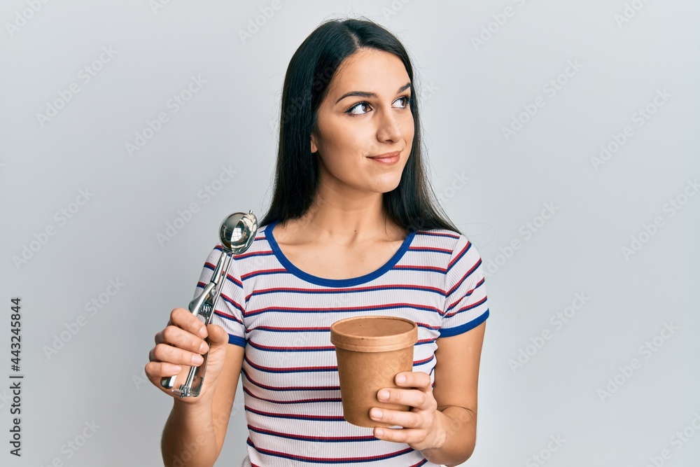 Young hispanic woman holding ice cream smiling looking to the side and staring away thinking. Young hispanic woman holding ice cream smiling looking to the side and staring away thinking.