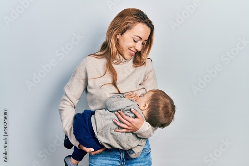 Young caucasian woman holding and hugging her son breastfeeding him, maternity lactation