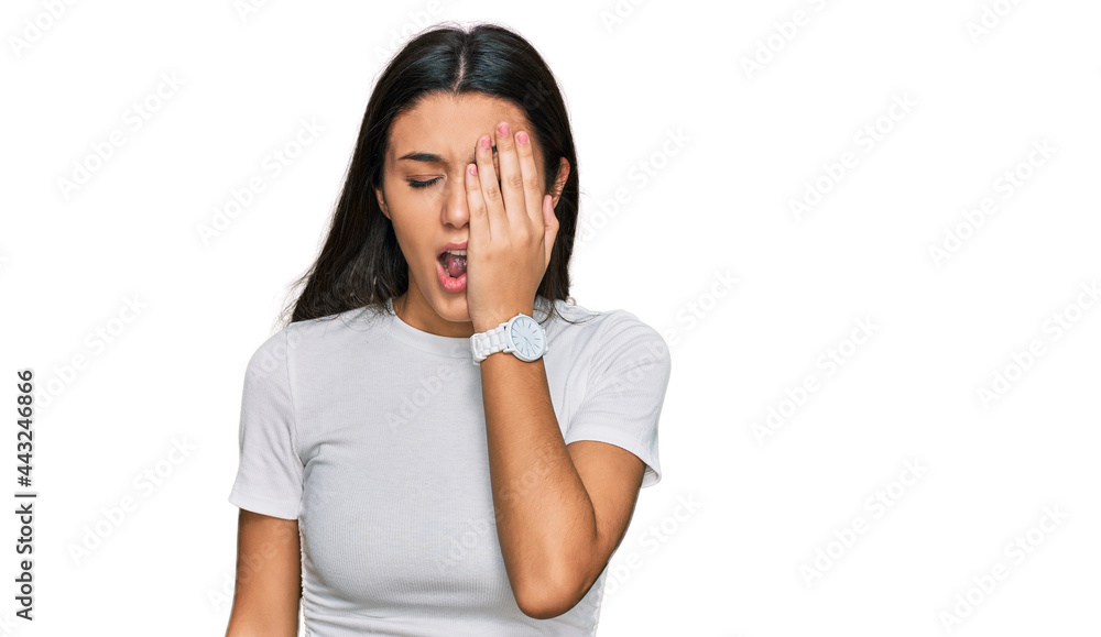 Young hispanic girl wearing casual white t shirt yawning tired covering half face, eye and mouth with hand. face hurts in pain. Young hispanic girl wearing casual white t shirt yawning tired covering half face, eye and mouth with hand. face hurts in pain.