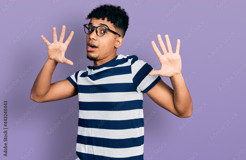 Young african american man wearing casual clothes and glasses afraid and terrified with fear expression stop gesture with hands, shouting in shock. panic concept. Young african american man wearing casual clothes and glasses afraid and terrified with fear expression stop gesture with hands, shouting in shock. panic concept.