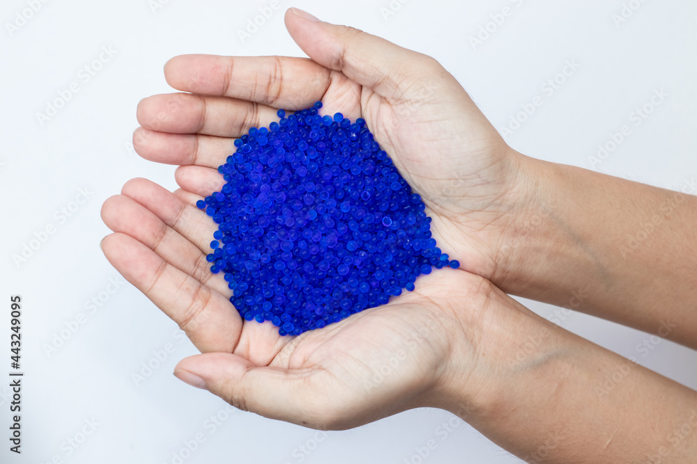 Close up of hand holding blue silica gel on white background, Granular Desiccant attract moisture for chemical. Close up of hand holding blue silica gel on white background, Granular Desiccant attract moisture for chemical.