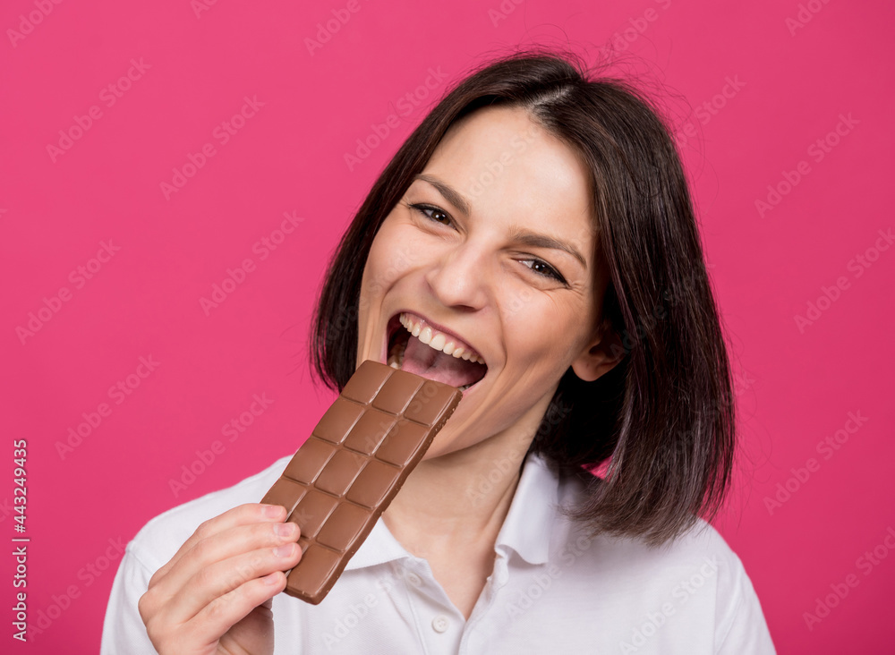 Beautiful young woman bites a bar of chocolate. Beautiful young woman bites a bar of chocolate.